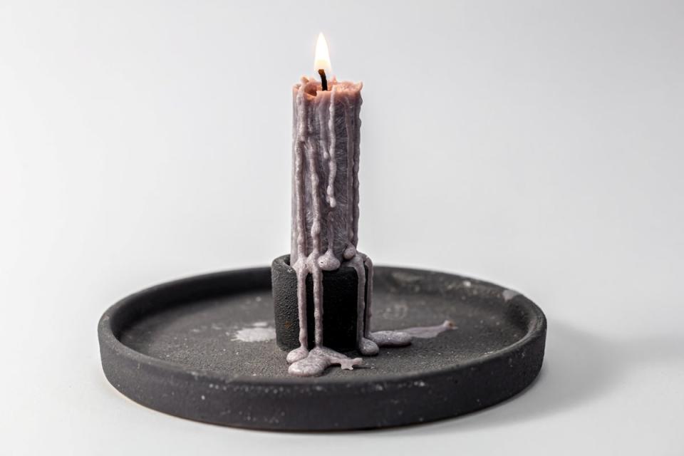 Candle with many wax drippings on side.