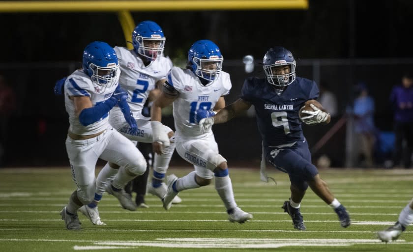 CALABASAS, CA - SEPTEMBER 24, 2021: Sierra Canyon running back Jason Jones (9) outruns Norco defenders Andrew Parker (25), Logan Grier (2), and Darius Ward (10) in the first half at Calabasas High School on September 24, 2021 in Calabasas, California.(Gina Ferazzi / Los Angeles Times)