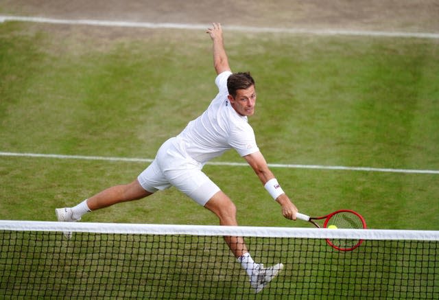 Neal Skupski lunges forward to hit a one-handed backhand volley