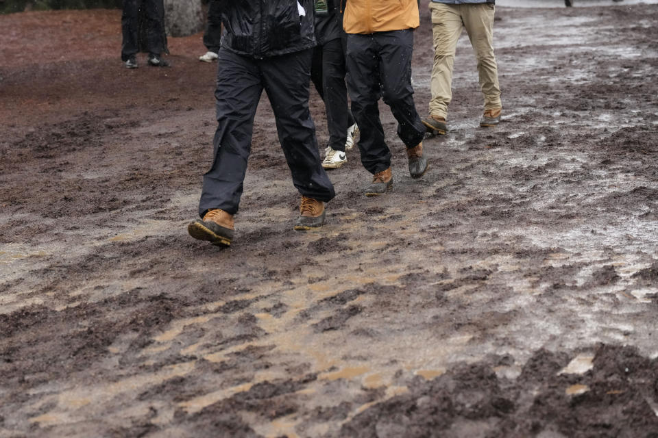 Patrons walk in the mud during the weather delayed third round of the Masters golf tournament at Augusta National Golf Club on Saturday, April 8, 2023, in Augusta, Ga. (AP Photo/Mark Baker)