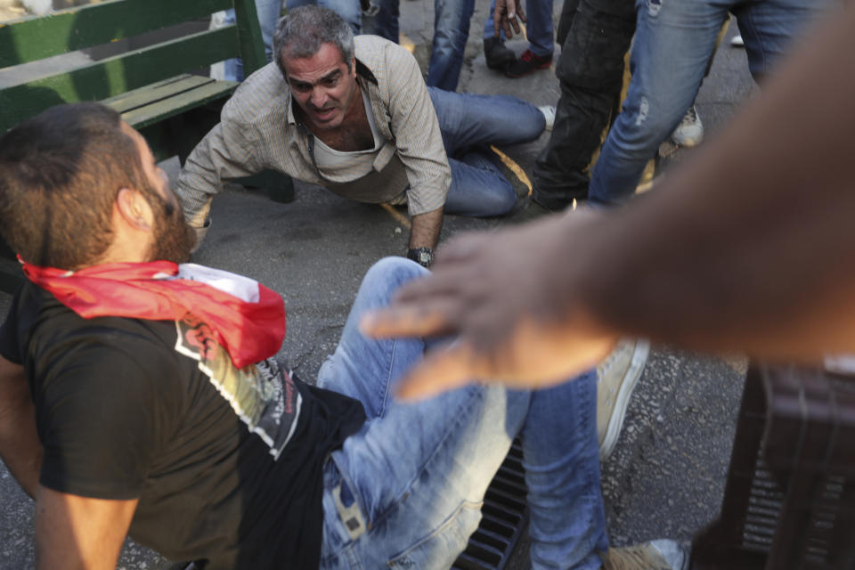 Protesters attack a supporter of President Michel Aoun, center, after they found an automatic rifle used in a shooting in his car, in the town of Jal el-Dib, north of Beirut, Lebanon, Wednesday, Nov. 13, 2019. The man opened fire over the heads of protesters in a town north of Beirut Wednesday, the second shooting incident in as many days as tensions rise in Lebanon between supporters and opponents of President Michel Aoun amid nationwide protests. (AP Photo/Hassan Ammar)