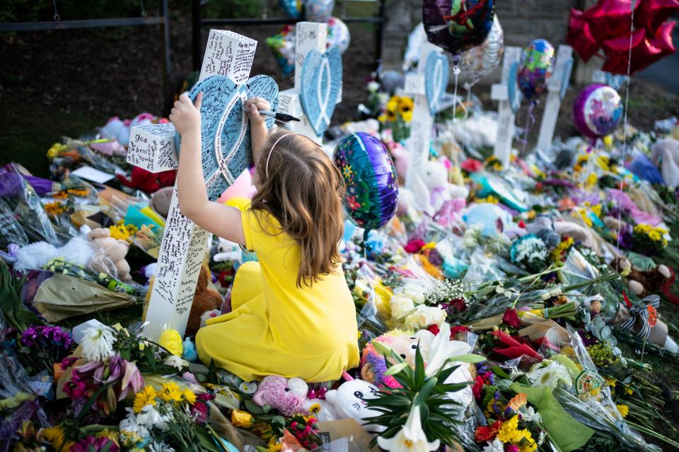 Kate Debusk, 8, a student at Julia Green Elementary School, writes a message on a marker remembering shooting victim Evelyn Dieckhaus, 9, at a memorial outside of The Covenant School in Nashville, Tenn., Thursday, March 30, 2023. A shooting at the school on Monday left three adults and three children dead.