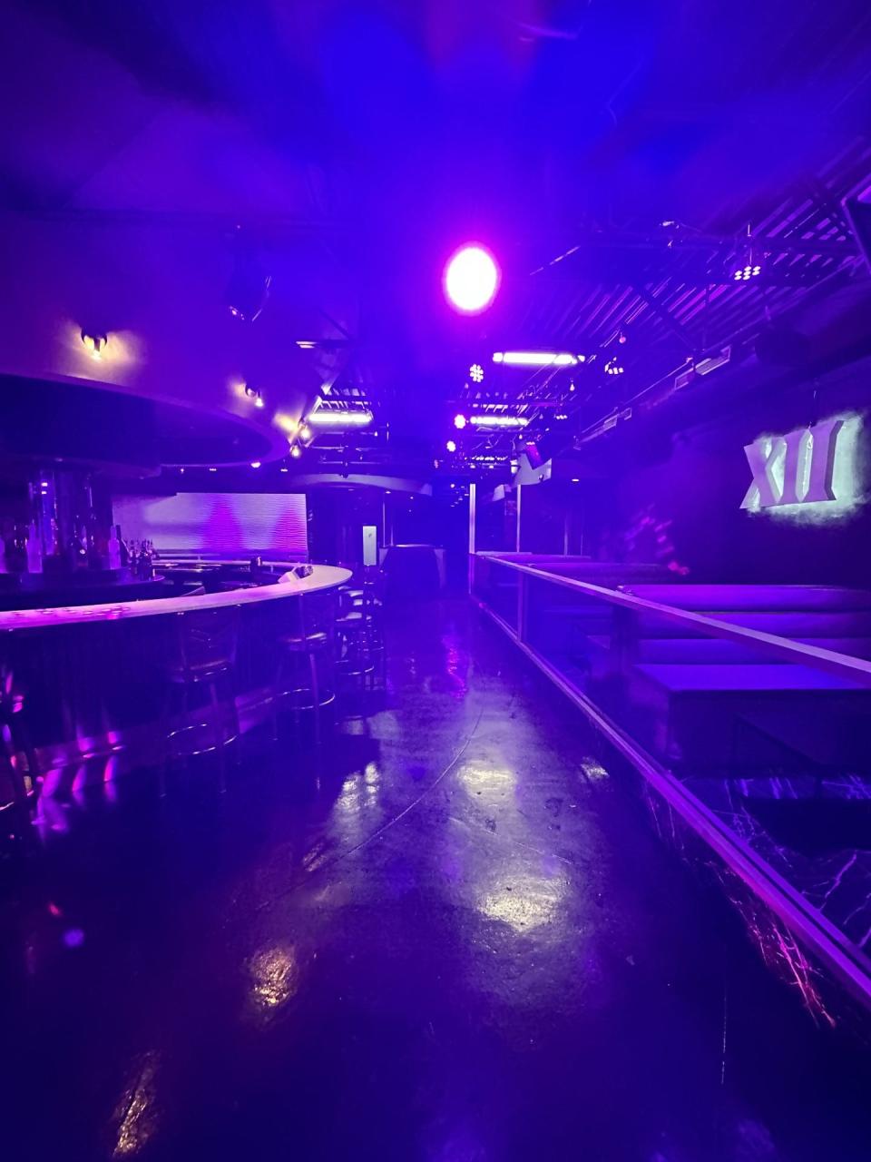 Inside DXII's purple-lit space is an open area with a round bar that customers on all sides can access. The booths on the right can be removed for live music nights.