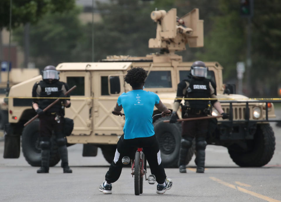 MINNEAPOLIS, MINNESOTA - MAY 29: A man rides a bicycle up to a law enforcement checkpoint after the city endured a night of protests and violence on May 29, 2020 in Minneapolis, Minnesota. The National Guard has been activated as protests continue after the death of George Floyd which has caused widespread destruction and fires across Minneapolis and St. Paul. (Photo by Scott Olson/Getty Images)