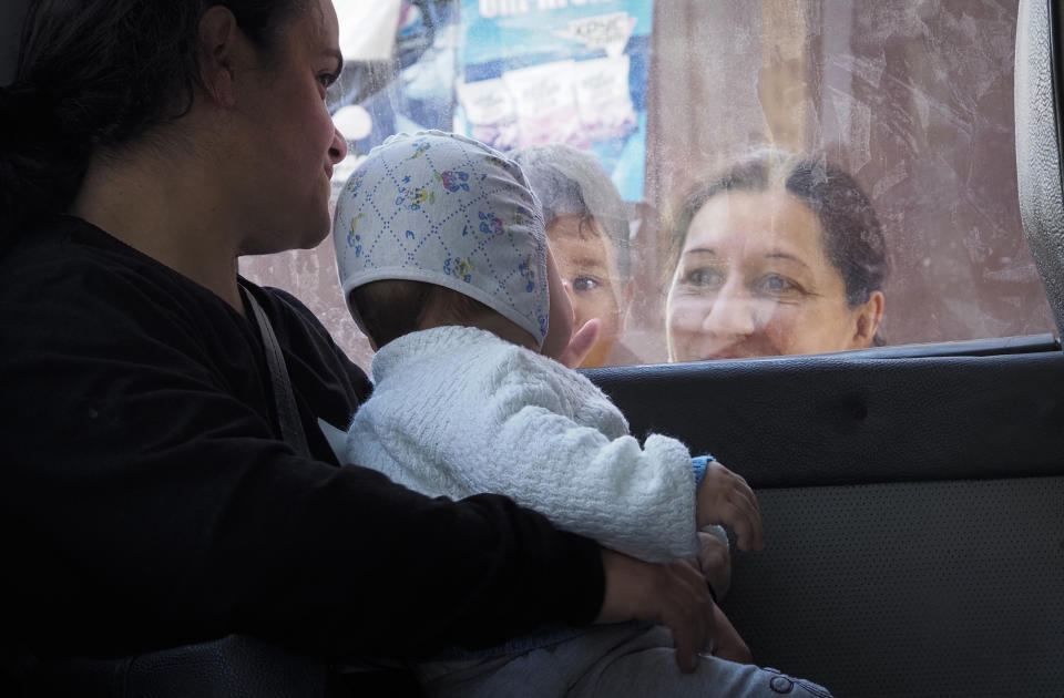 A woman says goodbye to her relatives as they sit in a bus preparing to leave Stepanakert, the separatist region of Nagorno-Karabakh, Friday, Oct. 30, 2020. The Azerbaijani army has closed in on a key town in the separatist territory of Nagorno-Karabakh following more than a month of intense fighting. (AP Photo)