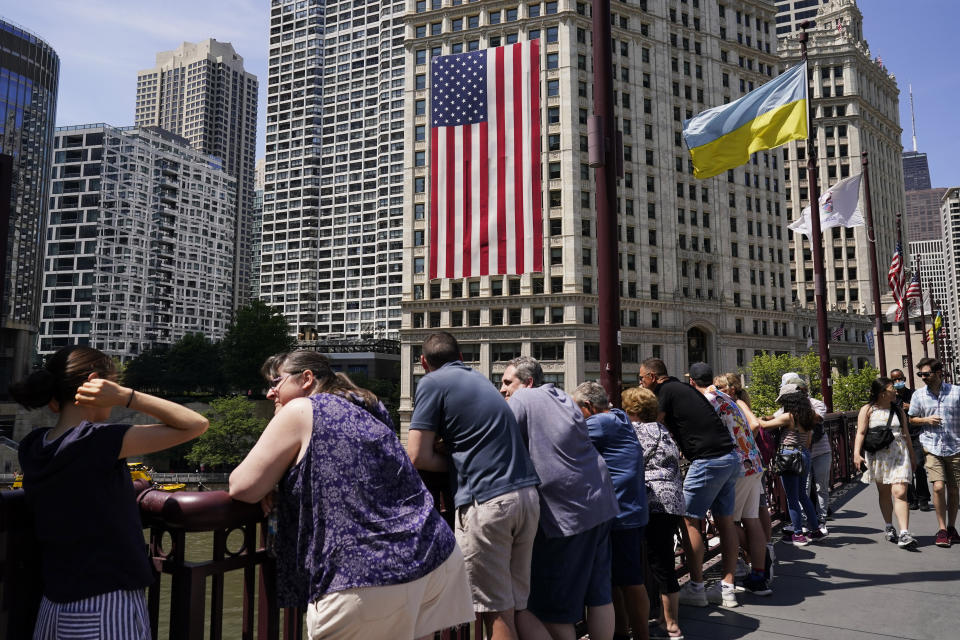 An American flag is seen on the Chicago River as people stand near the Chicago Riverwalk in Chicago, Monday, July 3, 2023, a day after heavy rains flooded Chicago streets and neighborhoods. (AP Photo/Nam Y. Huh)