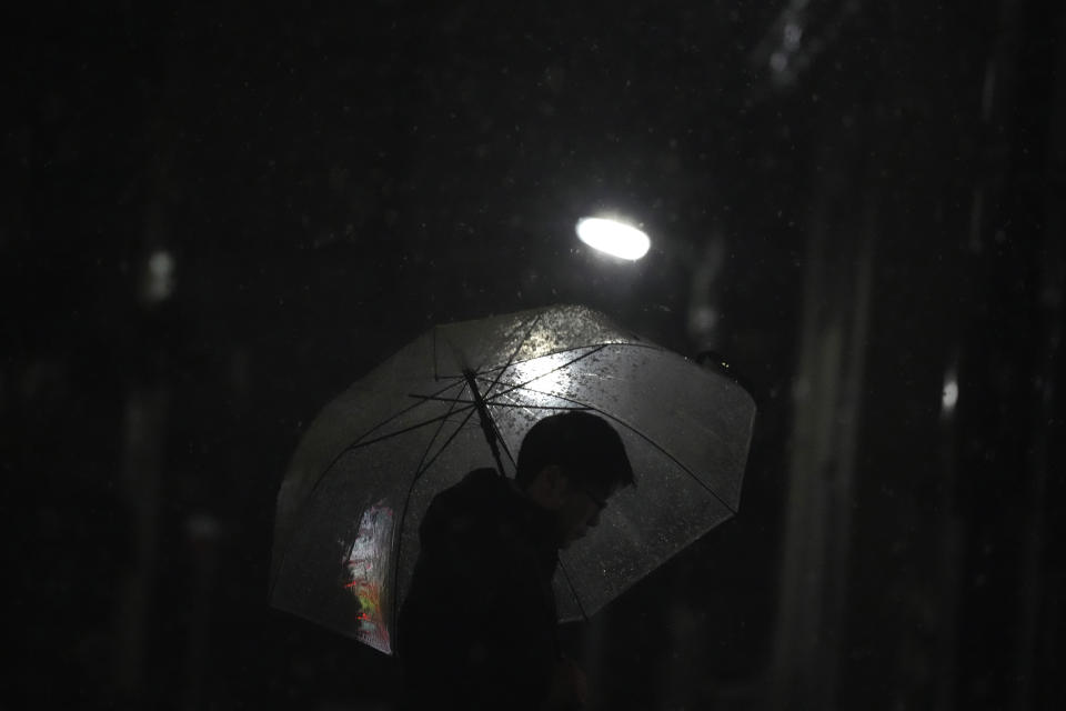 A person is silhouetted under an umbrella to shelter from a snowfall, in Tokyo, Monday, Feb. 5, 2024. Japan Meteorological Agency warned more Metropolitan areas braced for snowfall Monday. (AP Photo/Eugene Hoshiko)