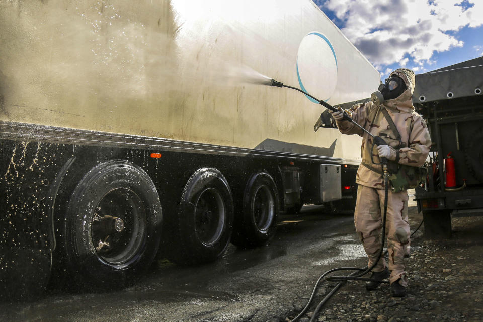 In this Sunday, March 1, 2020, photo, a Revolutionary Guard member disinfects a truck to help prevent the spread of the new coronavirus in the city of Sanandaj, western Iran. Wearing gas masks and waterproof fatigues, members of Iran's Revolutionary Guard now spray down streets and hospitals with disinfectants as the Islamic Republic faces one of the world's worst outbreaks of the new coronavirus. (Keyvan Firouzei/Tasnim News Agency via AP)