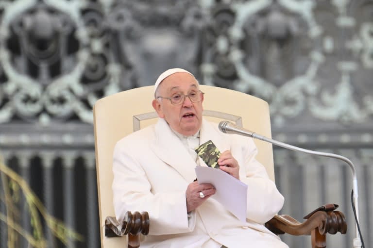 Le pape François tient le Nouveau Testament d'un soldat de 23 ans décédé en Ukraine, lors de son audience générale hebdomadaire sur la place Saint-Pierre au Vatican le 3 avril 2024 (Alberto PIZZOLI)