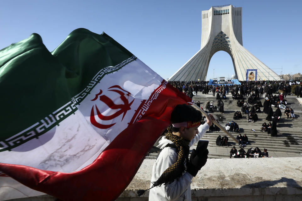 A boy carries an Iranian flag in front of Azadi tower in Tehran on Feb. 11, 2020. (Vahid Salemi / AP file)