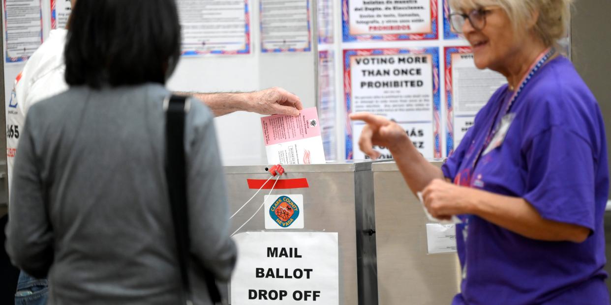 Voters drop their mail-in ballots in a box at a polling site.