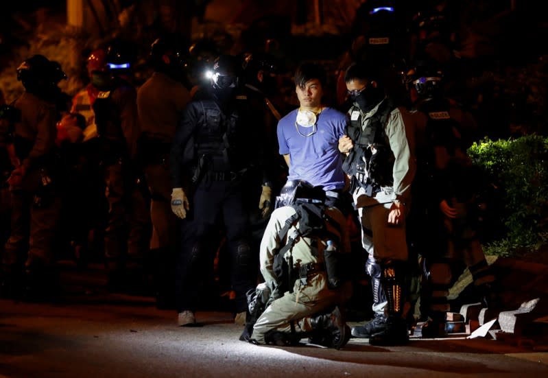 A protester is detained after he tried to leave Hong Kong Polytechnic University (PolyU) campus, in Hong Kong