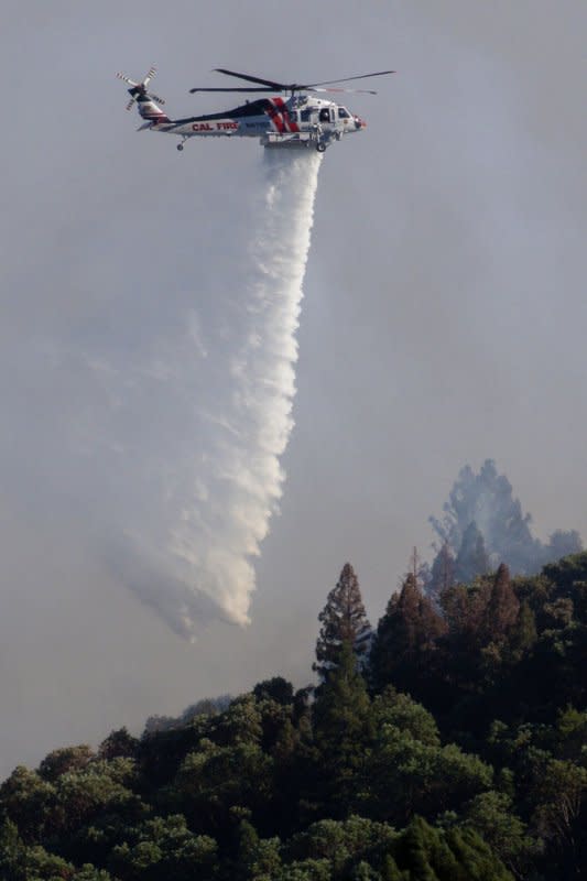 A helicopter drops water on a hotspot of the Point Fire, west of Geyserville, Calif., on Sunday. Photo by Peter DaSilva/UPI