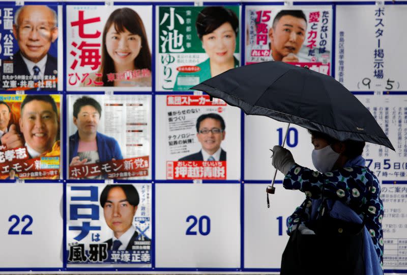 A passerby wearing a protective face mask walks past candidate posters including current governor Yuriko Koike for the upcoming Tokyo governor election during the spread of the coronavirus disease (COVID-19), in Tokyo