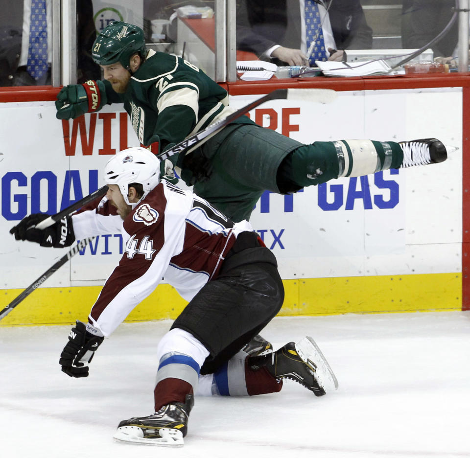 Colorado Avalanche defenseman Ryan Wilson (44) checks Minnesota Wild center Kyle Brodziak (21) into the boards during the first period of Game 4 of an NHL hockey first-round playoff series in St. Paul, Minn., Thursday, April 24, 2014. (AP Photo/Ann Heisenfelt)