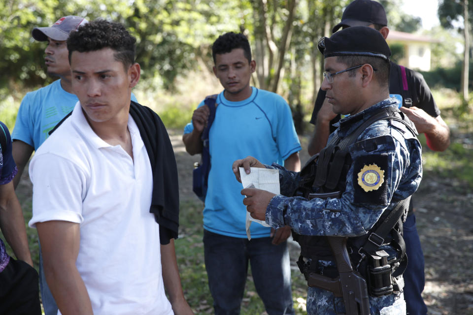 Honduras migrants trying to reach the United States show their ID card to a Guatemalan National Police agent after crossing the Honduran border, in Morales, Guatemala, Wednesday, Jan. 15, 2020. Hundreds of mainly Honduran migrants started walking and hitching rides Wednesday from the city of San Pedro Sula and crossed the Guatemala border in a bid to form the kind of migrant caravan that reached the U.S. border in 2018. (AP Photo/Moises Castillo)