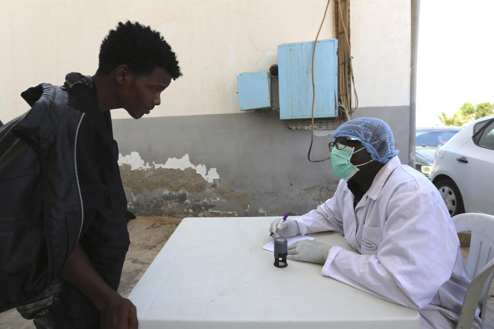 A doctor from the International Organization for Migration (IOM) checks a rescued migrant's identity before administering a Coronavirus test, in Ben Guerdane, southern Tunisia, Saturday June 12, 2021. Since the beginning of the year, over 600 people have died on the stretch of central Mediterranean coastline from Libya into Tunisia trying to reach Europe, according to the International Organization for Migration. (AP Photo/Mehdi El Arem)