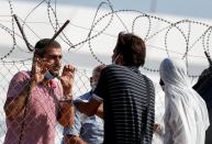 Men speak through the barbed wire at a new temporary camp for migrants and refugees, on the island of Lesbos