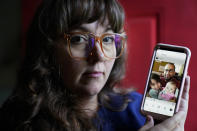 Allison Cullen, of Brockton, Mass., left, displays a family photo on her phone that shows her husband Flavio Andrade Prado, top, their son Gabriel Andrade-Cullen, bottom left, and their daughter Saoirse Andrade-Cullen, bottom right, Thursday, July, 22, 2021, at their home in Brockton. Prado, a Brazilian national, is being held by Immigration and Customs Enforcement, or ICE, at the Plymouth County House of Corrections. Cullen says she and her children haven't been able to visit her husband since before the pandemic. (AP Photo/Steven Senne)