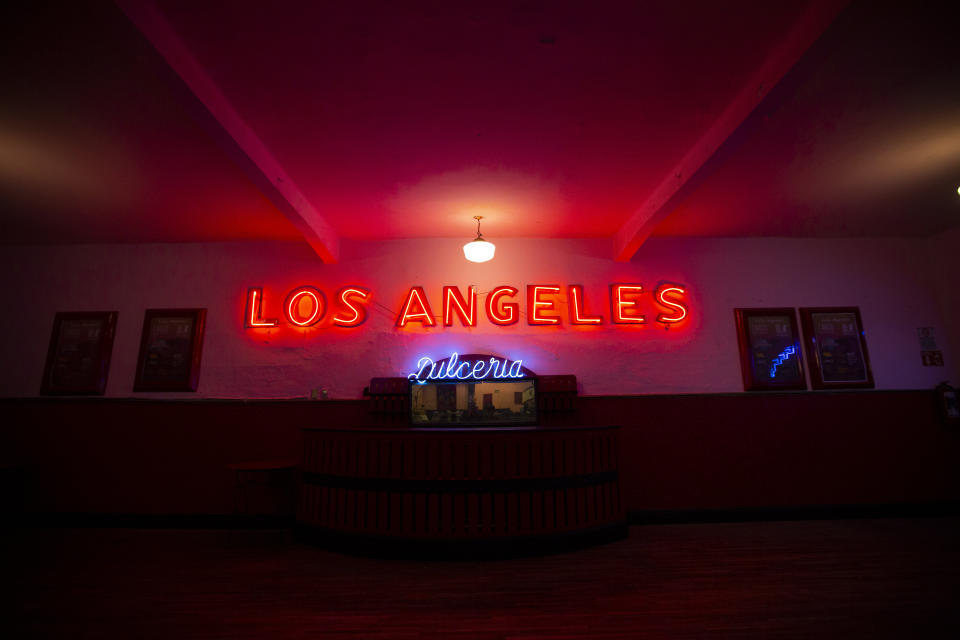 A Salon Los Angeles neon sign illuminates a service window during an event to raise money and keep open the iconic dance hall known as “The Cathedral of Mambo” amid the new coronavirus pandemic in Mexico City, Saturday, Sept. 5, 2020. Millionaires, writers, ambassadors, and movie stars danced here; now, shuttered for more than five months due to the pandemic, the owners of the fabled hall say they are in debt and may have to close and demolish it. (AP Photo/Fernando Llano)