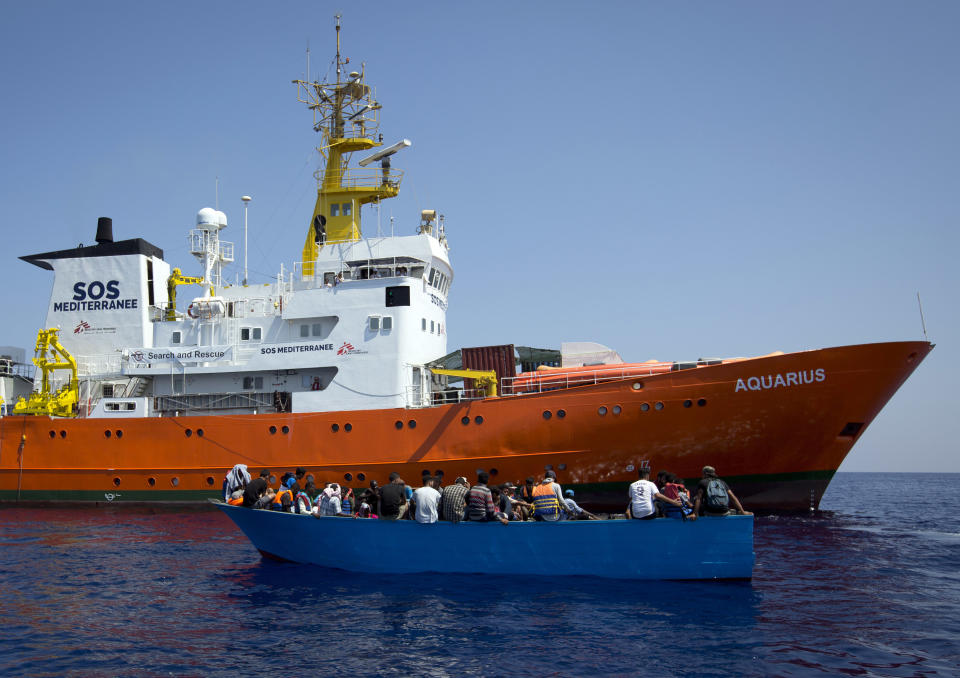 FILE - In this Aug. 29, 2017 file photo, African migrants float on a wooden boat next to a rescue ship during a search and rescue operation conducted by SOS Mediterranee's Aquarius ship and MSF (Doctors Without Borders) NGOs, in the Mediterranean Sea, north of Libyan coast. Italian prosecutors have ordered the seizure of a migrant rescue ship and accused the aid group Doctors Without Borders of illegally disposing 24 metric tons (26.5 tons) of medical and contaminated waste accumulated during nearly 50 rescues. (AP Photo/Darko Bandic, file)