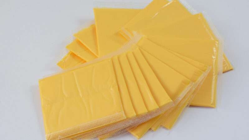 A fanned-out stack of American cheese slices, individually packaged.