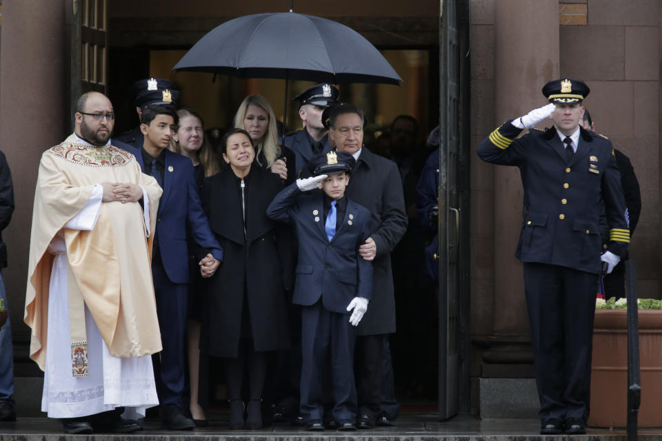 Mourners of Jersey City Police Detective Joseph Seals, including his wife Laura Seals, center left, watch as his casket is carried out of the church in Jersey City, N.J., Tuesday, Dec. 17, 2019. The 40-year-old married father of five was killed in a confrontation a week ago with two attackers who then drove to a kosher market and killed three people inside before dying in a lengthy shootout with police. (AP Photo/Seth Wenig)