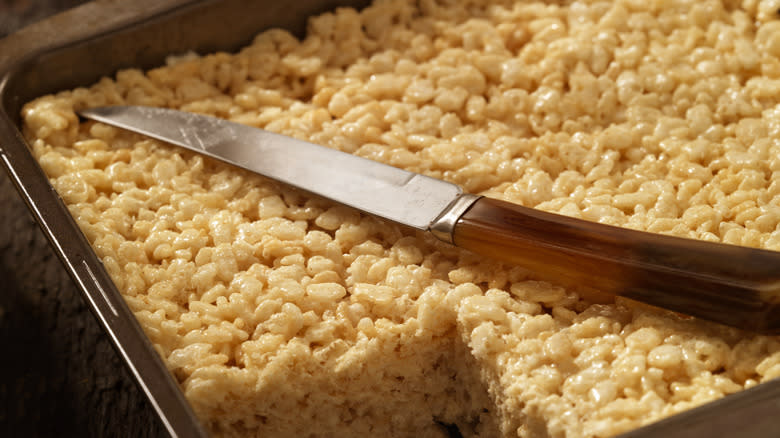 square cut from rice krispies treats in pan with knife