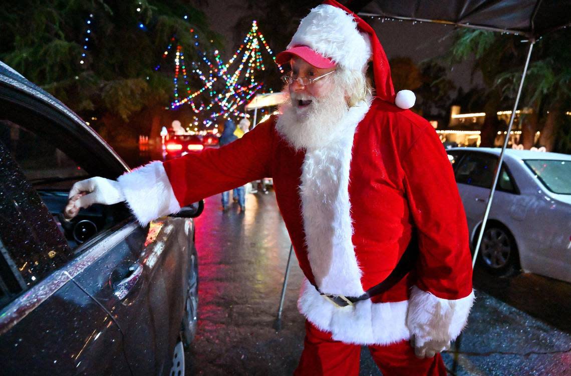 Santa greets children as cars pass along Christmas Tree Lane, which is celebrating its 100th year, Thursday, Dec. 1, 2022 in Fresno.