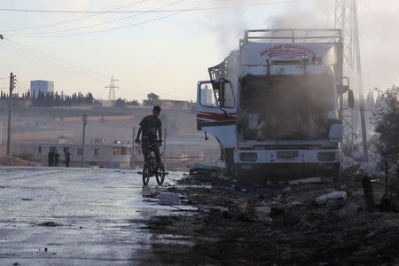 A boy rides a bicycle near a damaged aid truck after an airstrike on the rebel held Urm al-Kubra town, western Aleppo city, Syria September 20, 2016. REUTERS/Ammar Abdullah