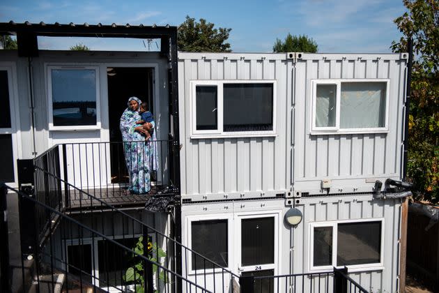 A mother poses for a photograph with her seven-month-old son outside a development of converted shipping containers in 2019 in Hanwell. (Photo: Chris J Ratcliffe via Getty Images)