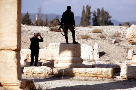 A Syrian army soldier takes a picture of a fellow soldier standing on ruins in the historic city of Palmyra, Syria March 4, 2017. REUTERS/Omar Sanadiki