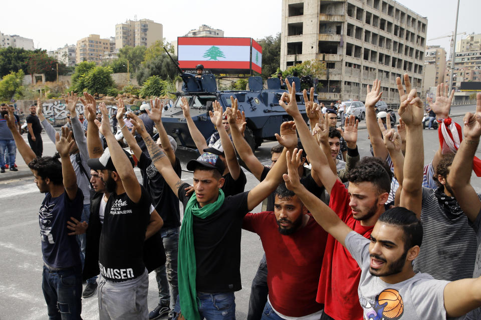 Anti-government protesters raise their hands as police disperse them from main highway in Beirut, Lebanon, Saturday, Oct. 26, 2019. The removal of the roadblocks on Saturday comes on the tenth day of protests in which protesters have called for civil disobedience until the government steps down. (AP Photo/Bilal Hussein)