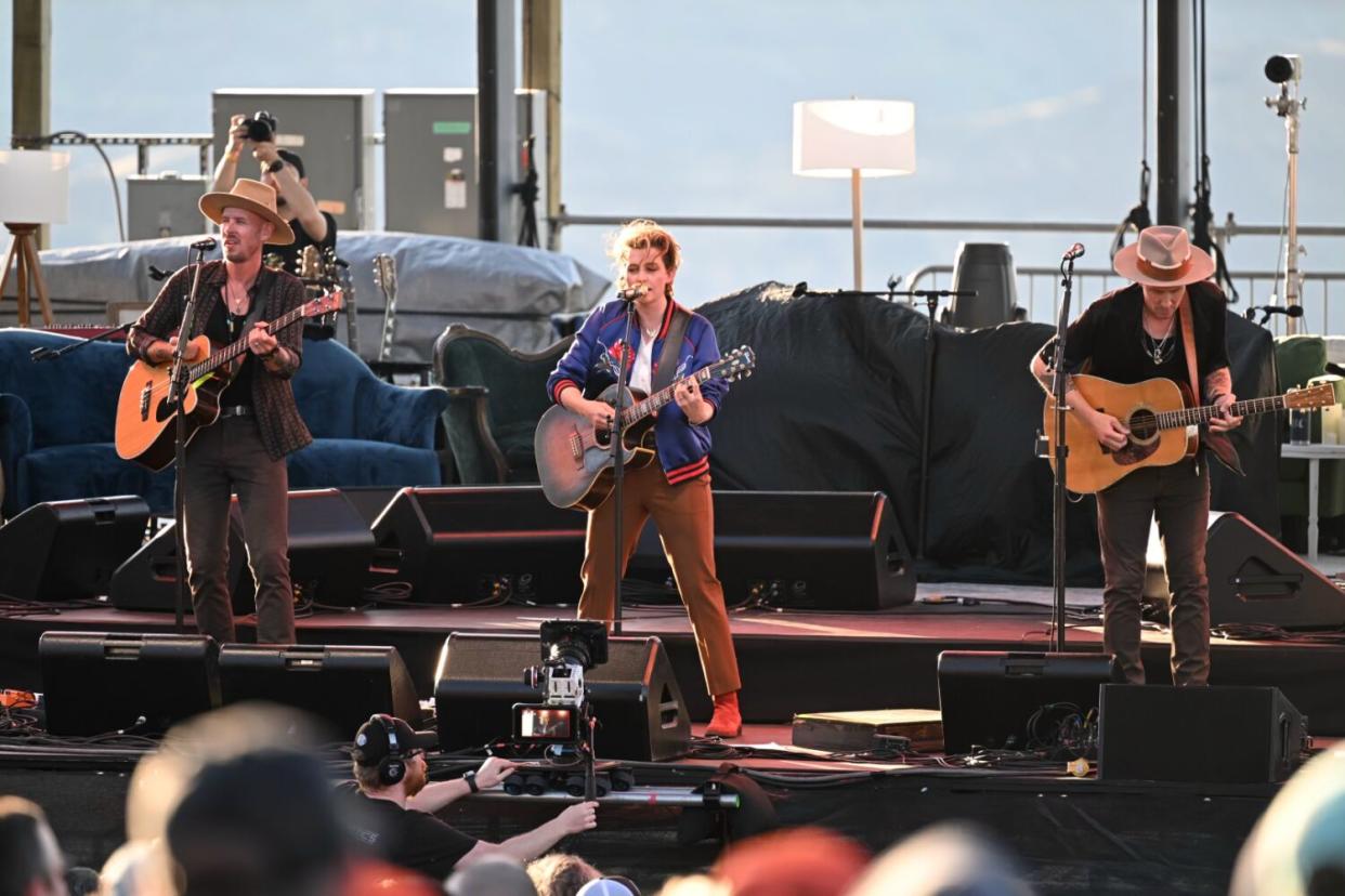 a woman and two men perform onstage