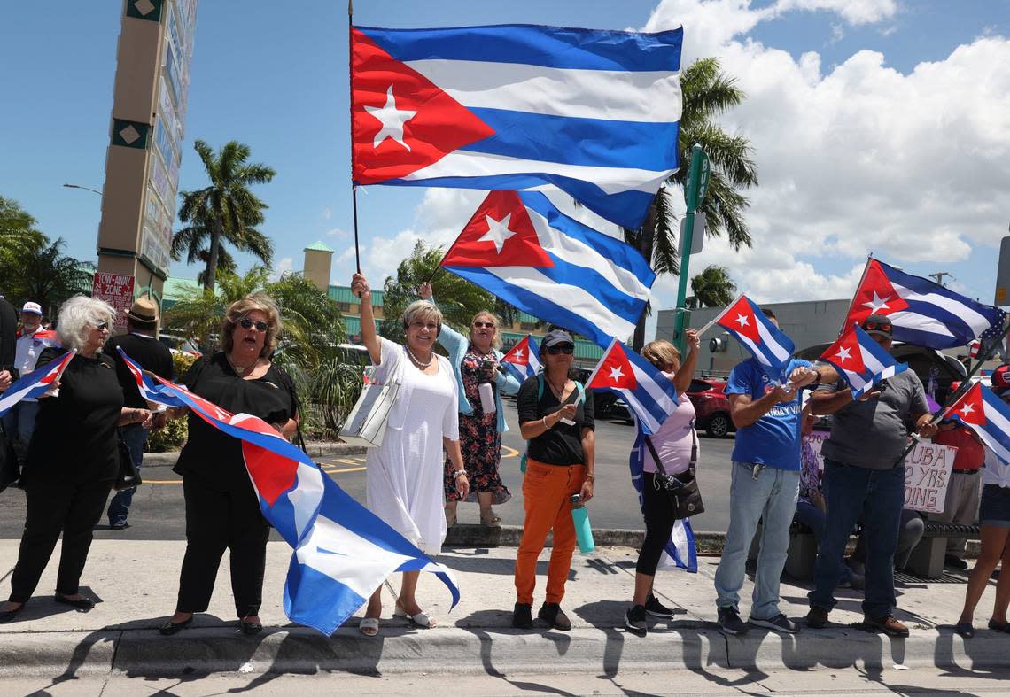 Cristina Maria Rodriguez Penton, 59, center, white dress, from Cuba on a church exchange program, waves a flag during a Cuban flag distribution along SW 40th Street on Monday, July 11, 2022 outside of La Carreta on Bird Road. The Assembly of the Cuban Resistance held a series of activities to commemorate the first anniversary of the July 11 mass protests in Cuba.