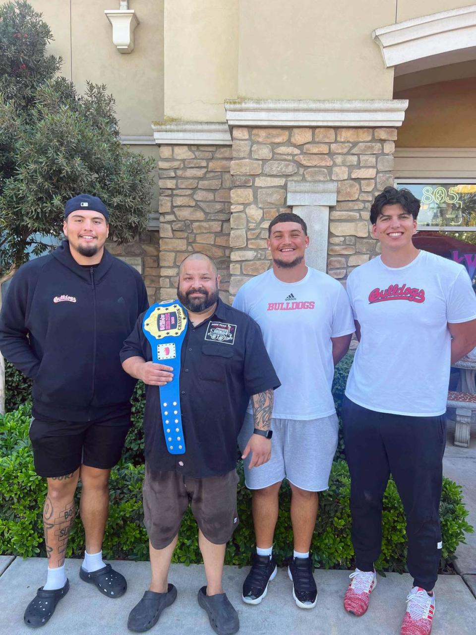 Jonathan Carbajal poses with his Meat Market Mania title belt with the Fresno State Bulldogs’ offensive linemen Julian Polendo, on the left, Jacob Spomer, to the right of Carbajal, and Hayden Pulis, on the far right. The three football players were celebrity judges during the competition this year.