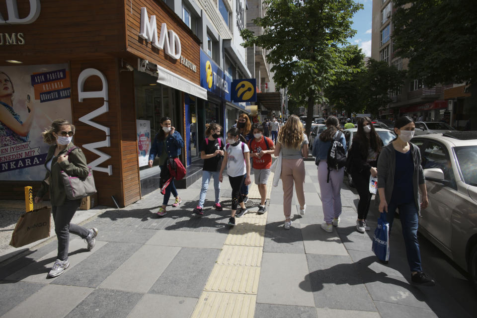 People walk along a popular street, in Ankara, Turkey, Wednesday, June 3, 2020, days after the government lifted a series of restrictions imposed to fight the coronavirus pandemic. People crowded popular streets and parks while restaurants and cafes welcomed sit-in customers and beaches and museums reopened as part of Turkey's broadest easing of coronavirus restrictions. (AP Photo/Burhan Ozbilici)