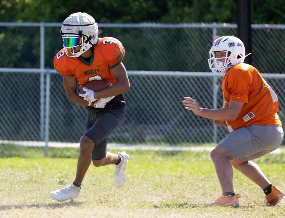 Dolphin Isaac Paul runs the ball during practice. Mosley football hit the practice field for spring drills Thursday, May 6, 2022.