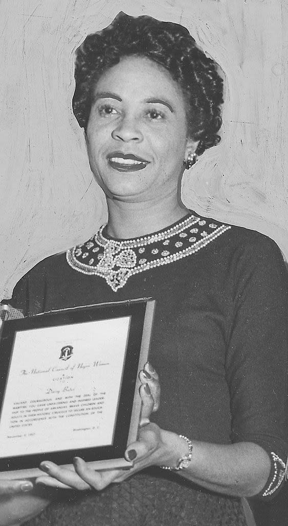 Bates smiling and holding a plaque