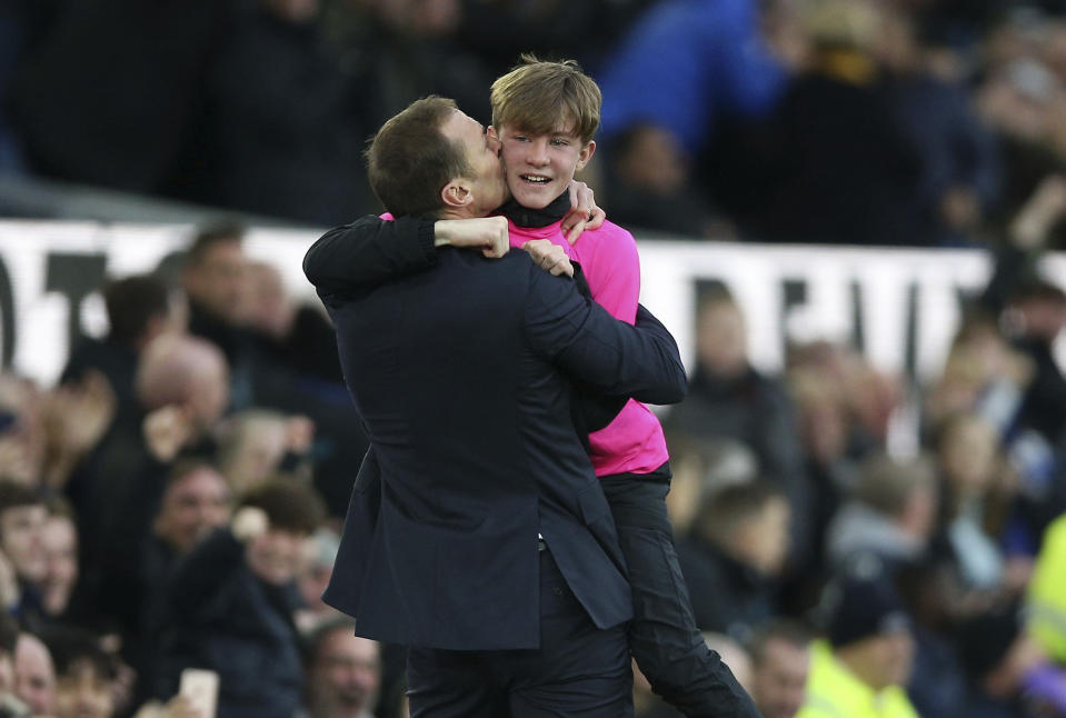 Everton caretaker manager Duncan Ferguson celebrates with a ball boy after seeing his side score their third goal, during the English Premier League soccer match between Everton and Chelsea at Goodison Park, in Liverpool, England, Saturday, Dec. 7, 2019. (Nigel French/PA via AP)