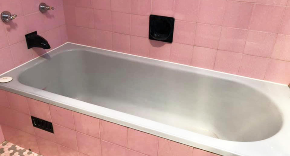 An old bathtub in a pink 1950's bathroom. 