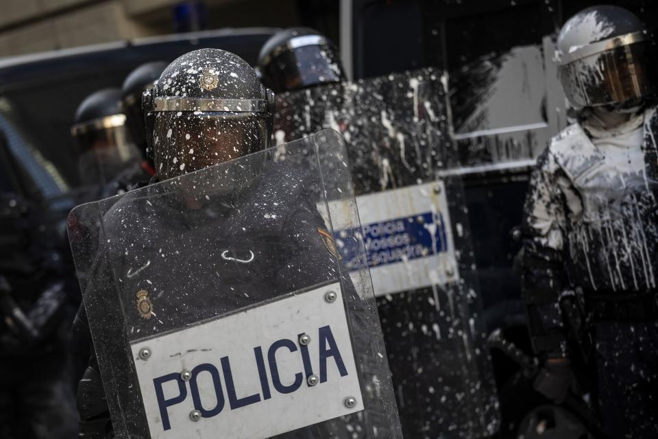 Catalan regional police covered in paint trhown by pro-independence demonstrators in Barcelona, Spain, Friday, Oct. 18, 2019. Various flights into and out of the region are cancelled Friday due to a general strike called by pro-independence unions and five marches of tens of thousands from inland towns are expected converge in Barcelona's center on Friday afternoon for a mass protest with students to and workers who are on strike. (AP Photo/Bernat Armangue)