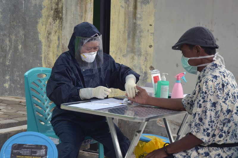 A medical worker wearing a protective suit draws blood from a man for the preliminary coronavirus disease (COVID-19) blood test in Pekanbaru