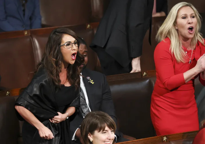 Reps. Lauren Boebert in black, shouts loudly as Marjorie Taylor Greene stands to scream. 