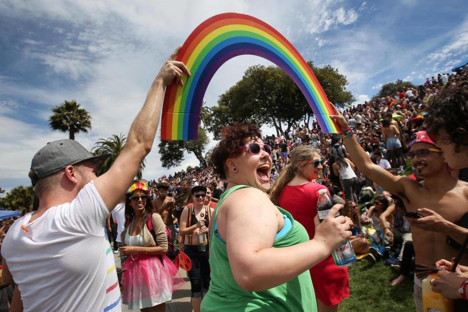 Daniela Lopez smiles as she walks under a rainbow held by two men during a gay pride celebration in Dolores Park on June 27, 2015 (Elijah Nouvelage/Getty Images)