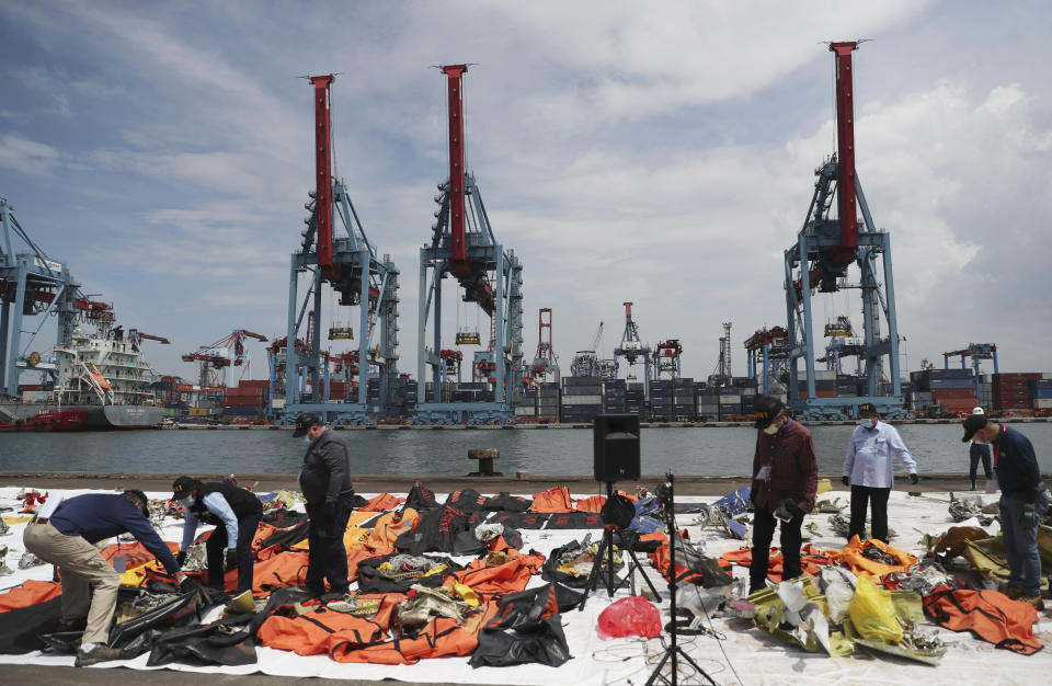 Investigators from Indonesian National Transportation Safety Committee (KNKT) and U.S. National Transportation Safety Board (NTSB) inspect debris found in the waters around the location where a Sriwijaya Air passenger jet crashed, at the search and rescue command center at Tanjung Priok Port in Jakarta, Indonesia Saturday, Jan. 16, 2021. (AP Photo/Achmad Ibrahim)