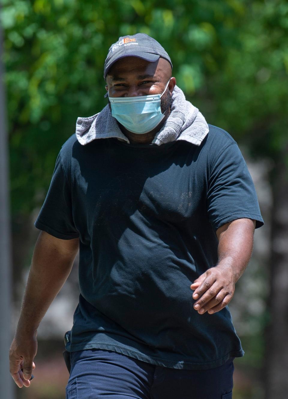 David Ford of Gluckstadt, Miss., dons a towel to protect his neck from the sun's heat and harmful rays as he walks in Strawberry Patch Park in Madison, Miss., Monday, June, 13, 2022.