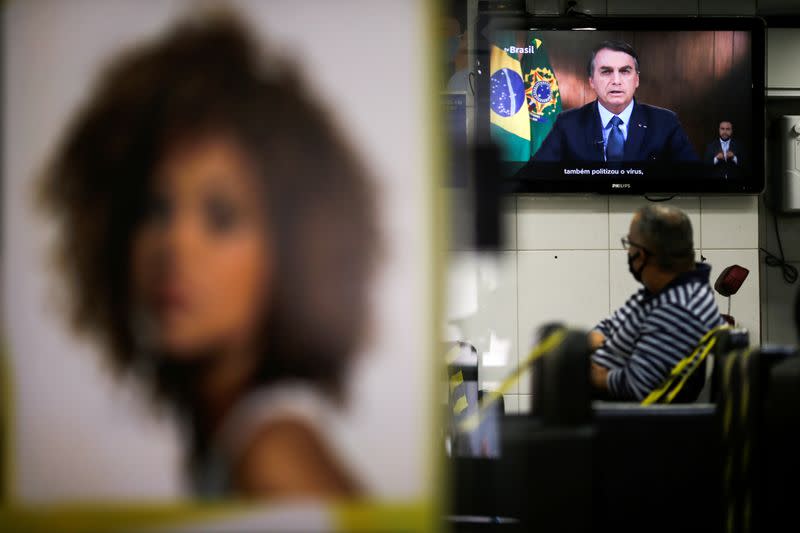 Brazil's President Jair Bolsonaro is seen on a tv screen in a beauty salon as he speaks in a video recorded speech for the 75th session of the United Nations General Assembly, in Brasilia