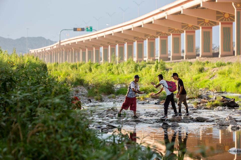 At left, a Mexican man receives cash from Venezuelan migrants in order to buy them food at the Rio Grande after the migrants pleaded for help in order to feed their families, who had not eaten for hours as they awaited processing by Customs and Border Protection.