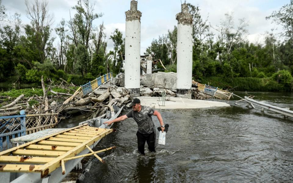 A local resident crosses the Siversky Donets River on a destroyed bridge in Bohorodychne village - OLEG PETRASYUK/EPA-EFE/Shutterstock/Shutterstock